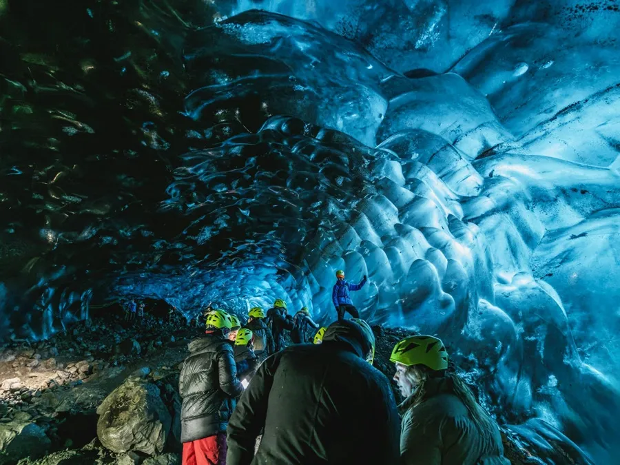 Group-of-explorers-in-an-illuminated-ice-cave.webp