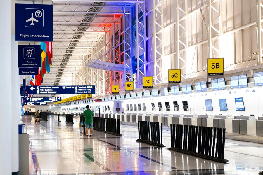 Airport check-in hall with flight information signs and rows of desks